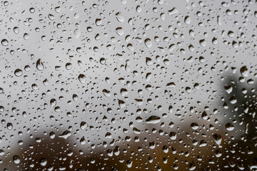 abstract drops on a window glass with blurred background close up , rain macro