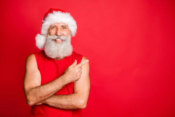 Portrait of sporty cristmas father showing his index finger smiling recommend winter sales wearing santa claus hat cap isolated over red background