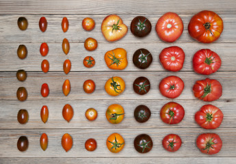 Different varieties of tomatoes on a wooden background.