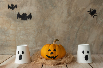 Front view of Halloween pumpkins, Yellow pumpkins ghost and paper cup ghost on cement wall...