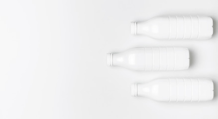 White plastic bottle containers for dairy products on light gray background top view flat lay. Plastic Kefir Yogurt Milk Bottle. Packaging template mockup. Layout for your design
