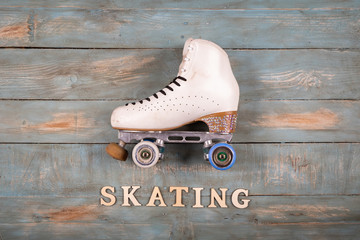 artistic roller skates on a wood background with skating word formed with white letters