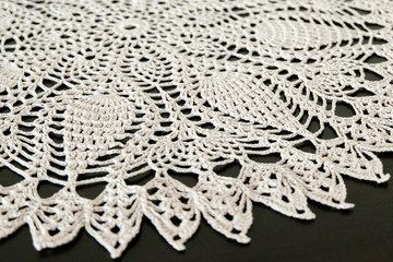 Part of a lace doily on a dark background. Handwork, a beautiful napkin.