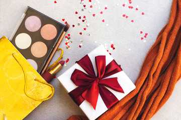 box of highlighter and glitter and lipstick, brush  on gift bag, gift box and heart confetti with orange scarf 