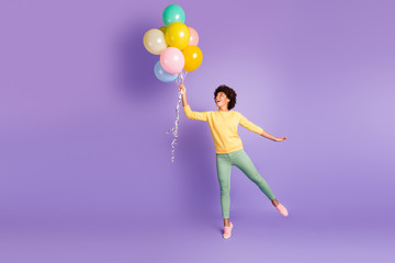 Fototapeta na wymiar Full length profile side photo of amazed funky funny dark skin girl hold many baloons think she can fly in the sky enjoy rejoice wear trendy green sweater outfit isolated over violet color background