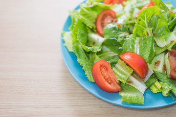 Delicious and healthy fresh organic tomato and romaine lettuce salad with vinaigrette dressing sauce on a wooden surface