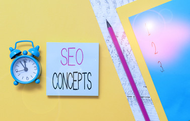 Conceptual hand writing showing Seo Concepts. Concept meaning a process of increasing the quality of website traffic Notepads marker colored paper sheets alarm clock wooden background