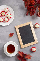 Blackboard with Autumn red leaves, candies and tea on gray table. Top view, space for text. Teacher's day, study, confectionery concept