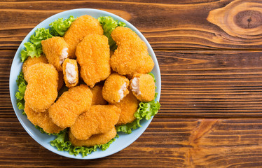 Chicken nuggets in plate on rustic background