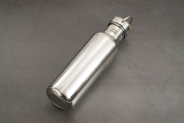 Durable, high quality reusable stainless steel bottle on gray background as alternative to plastic bottles. Toxin, BPA, plastic free zero waste option for drinking tap water at home or at the office.