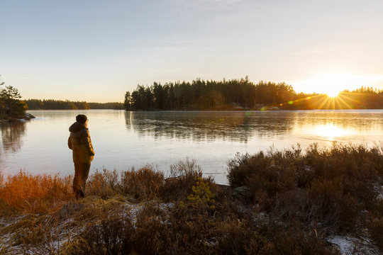 Mature woman standing next to Lake Skiren at sunset in Sweden
