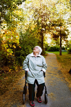 Senior woman sitting on a walking frame in park