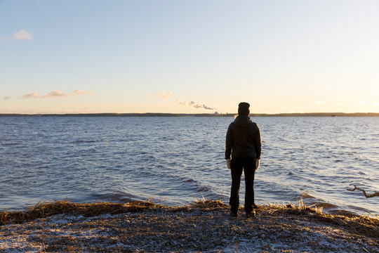 Mature woman standing next to Lake Glan at sunset in Sweden