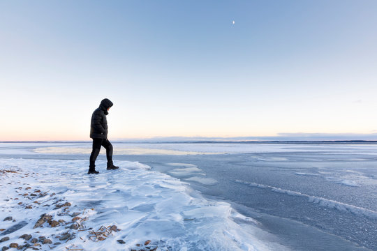 Man walking on frozen Glan lake at sunset in Ostergotland, Sweden