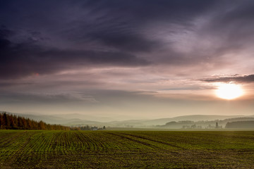 Fototapeta na wymiar View of the Ore Mountains in autuum, foggy meadow in the background and forests, dark clouds and sunset, View of the Ore Mountains, Germany
