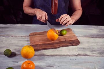 Young chef in kitchen holding knife and preparing juice. Food concept.