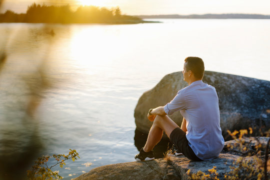 Man sitting on rock by sea
