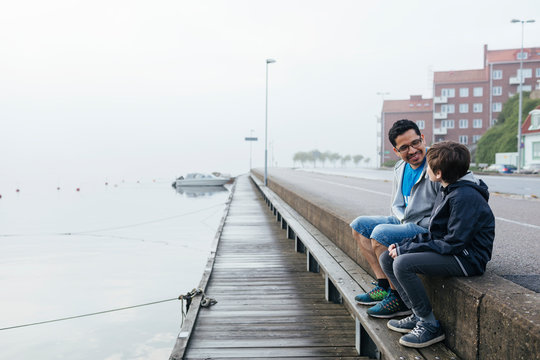 Father and son sitting by harbour