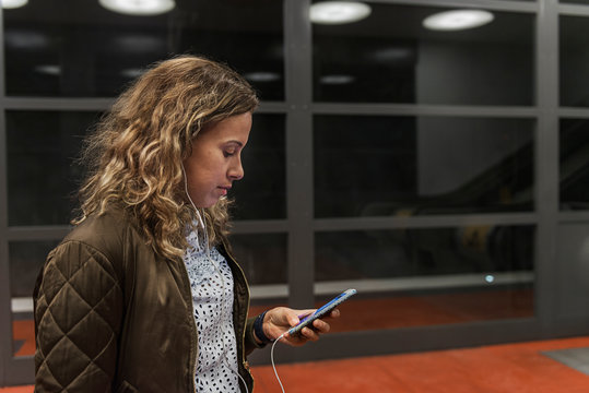 Young woman looking at cell phone at subway station