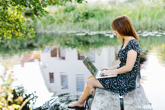 Young woman using laptop on jetty