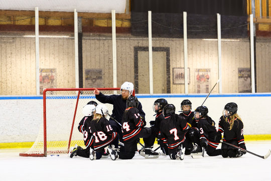 Girls listening to their coach during ice hockey training