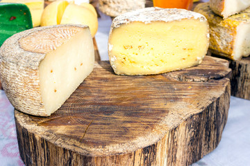 Large selection of cheese varieties on a wooden table background.