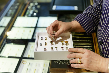 Hands of goldsmith examining box of rings