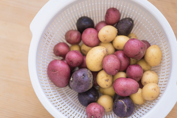 Tricolor mini potatoes in a basket on a wooden table washed and cleaned.