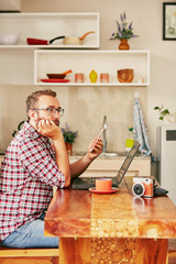 Modern bearded man using cellphone and drinking coffee with laptop.