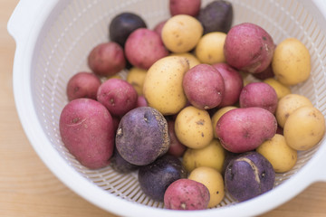 Tricolor mini potatoes in a basket on a wooden table washed and cleaned.