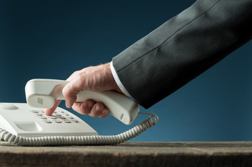 Hand of a businessman holding telephone handset dialing phone number
