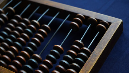 Vintage wooden abacus close up. Counting wooden knuckles. Part of the old end of the abacus on a dark blue background.