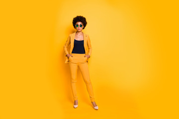 Full length photo of serious elegant attractive afro american lady put hands in pockets look bossy like real executive manager wear fashionable clothing isolated over yellow color background