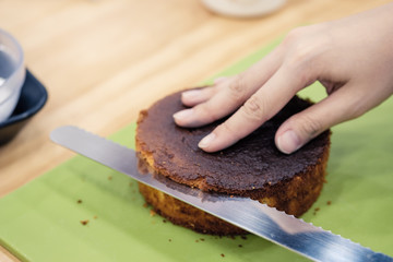 Making a layer cake. Cutting the top off of cakes with a serrated knife to level cake.