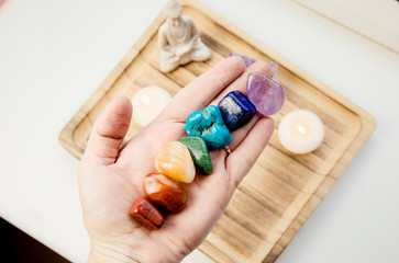 Woman hand sowing all seven color chakra crystal stones. Chakra energy flow healer concept.