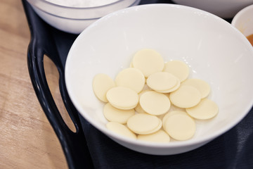 White chocolate chips in a bowl for melting, preparing ingredients to make a cake.