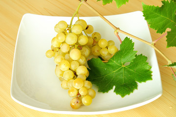 bunch of white grapes with its green leaves