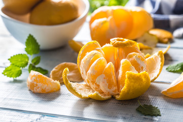 Tangerines with peel and mellisa herbs on table. Ripe fresh tropical fruit on wooden board