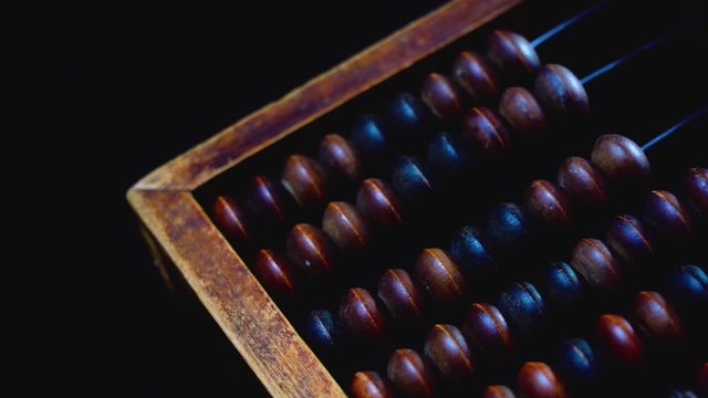 Vintage wooden abacus. Part of the old end of the abacus on a dark background.