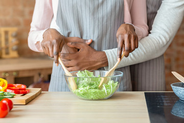 Cropped image of married couple cooking together at kitchen