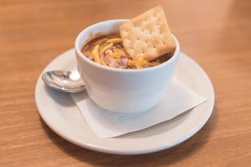 A bowl of spicy chili and crackers with a spoon.