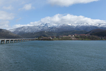 puente de Riaño con pantano lleno y nieve en las montañas