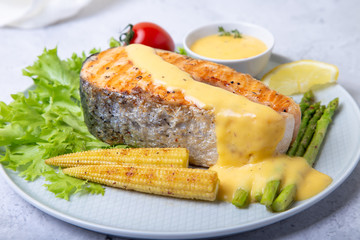 Grilled salmon with asparagus, corn mini and hollandaise sauce. Close-up.
