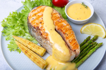 Grilled salmon with asparagus, corn mini and hollandaise sauce. Close-up.