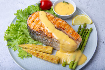 Grilled salmon with asparagus, corn mini and hollandaise sauce. Close-up.