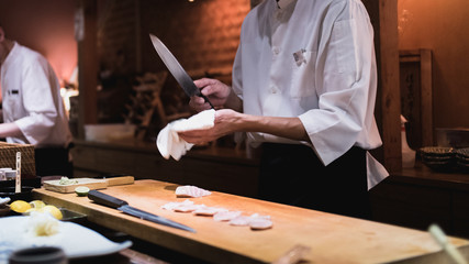 Chef wiping knife, motion. Omakase style Japanese traditional.