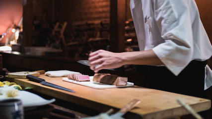 Chef preparing slicing fish, otoro. Omakase style Japanese traditional.