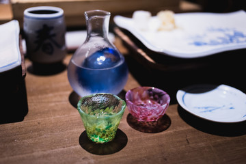 Colorful glass transparent Sake cups on a wooden table in an restaurant environment.
