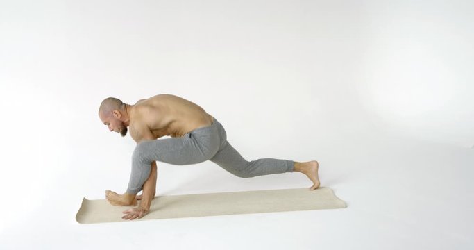 Practice of yoga. Sporty man with bare torso barefoot yoga position training on white background