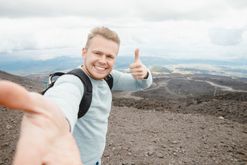 Tourist takes selfie on top of volcano Mount Etna, Sicily Italy. Mountain travel concept